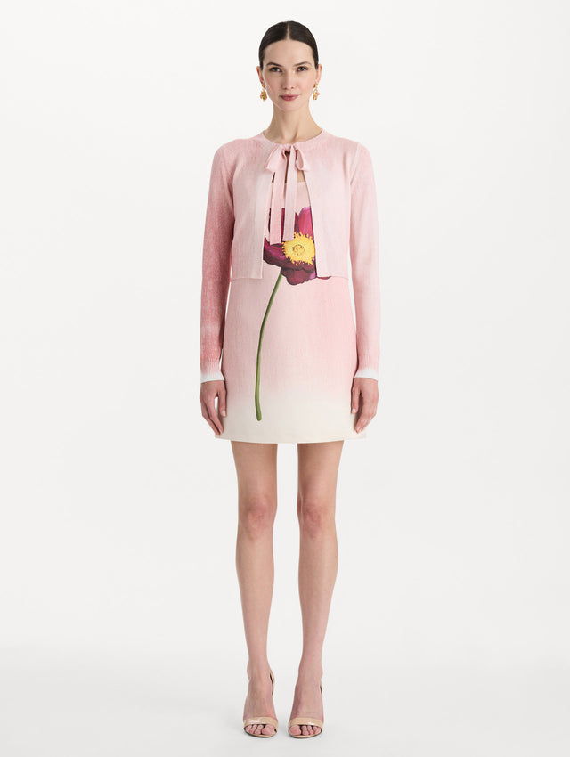 The model is wearing the botanical tie-neck cardigan with a floral print in the color blush. Front view.