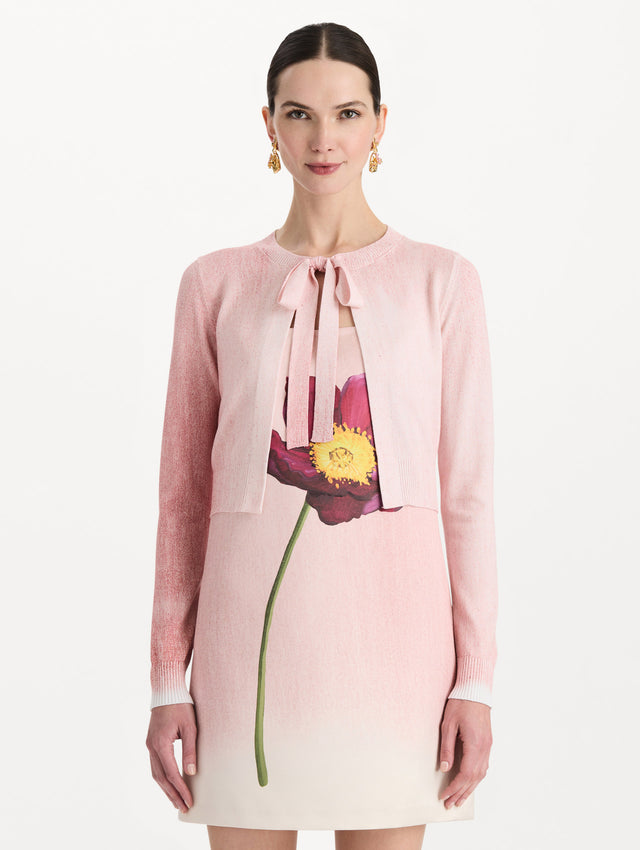 The model is wearing the botanical tie-neck cardigan with a floral print in the color blush. Front view.