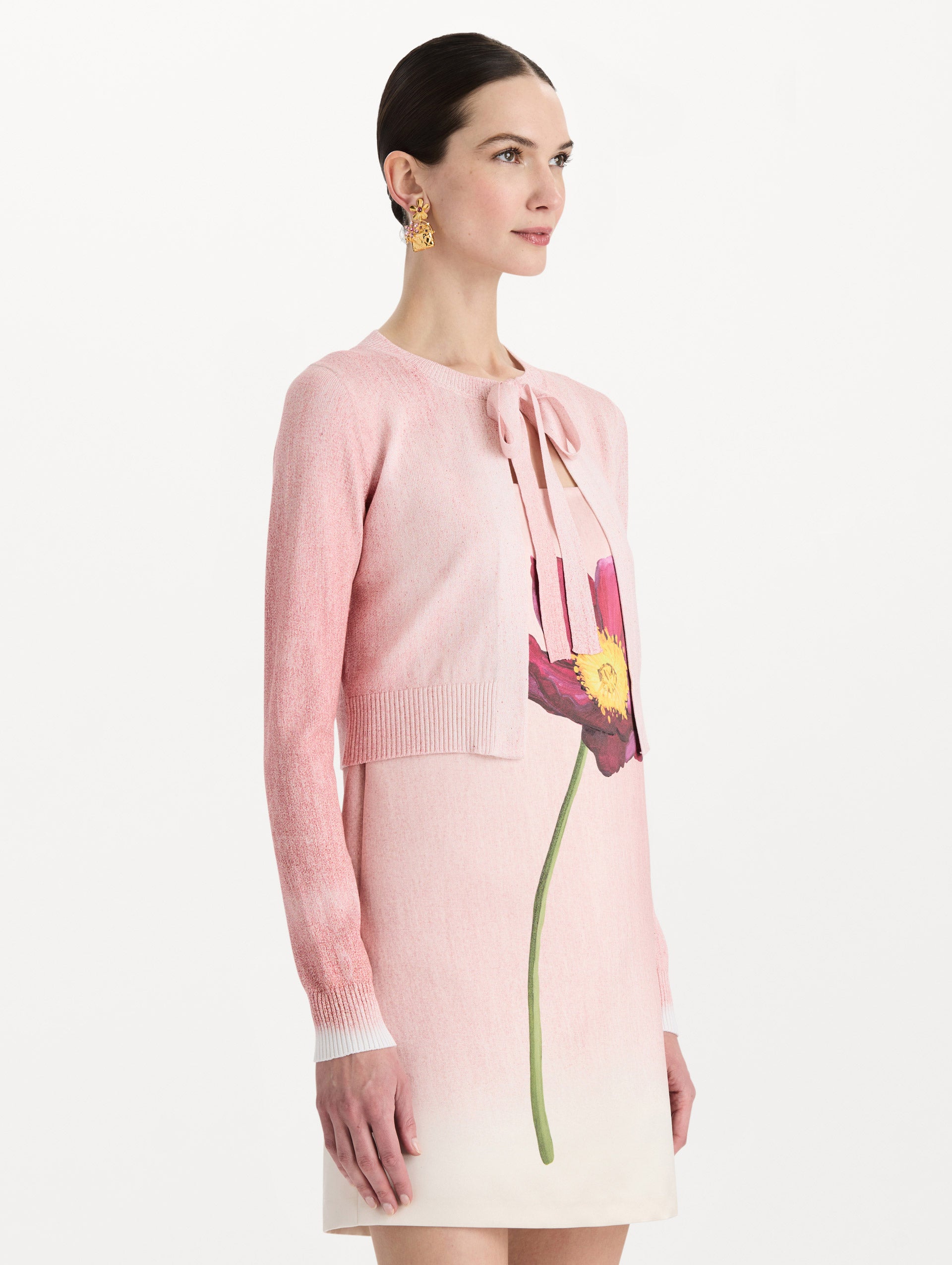 The model is wearing the botanical tie-neck cardigan with a floral print in the color blush. Side view.