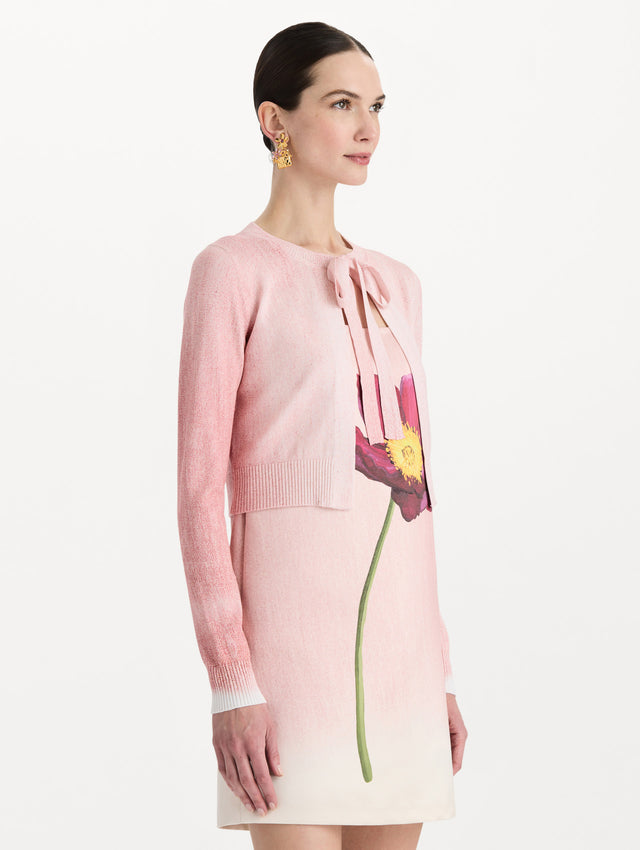 The model is wearing the botanical tie-neck cardigan with a floral print in the color blush. Side view.