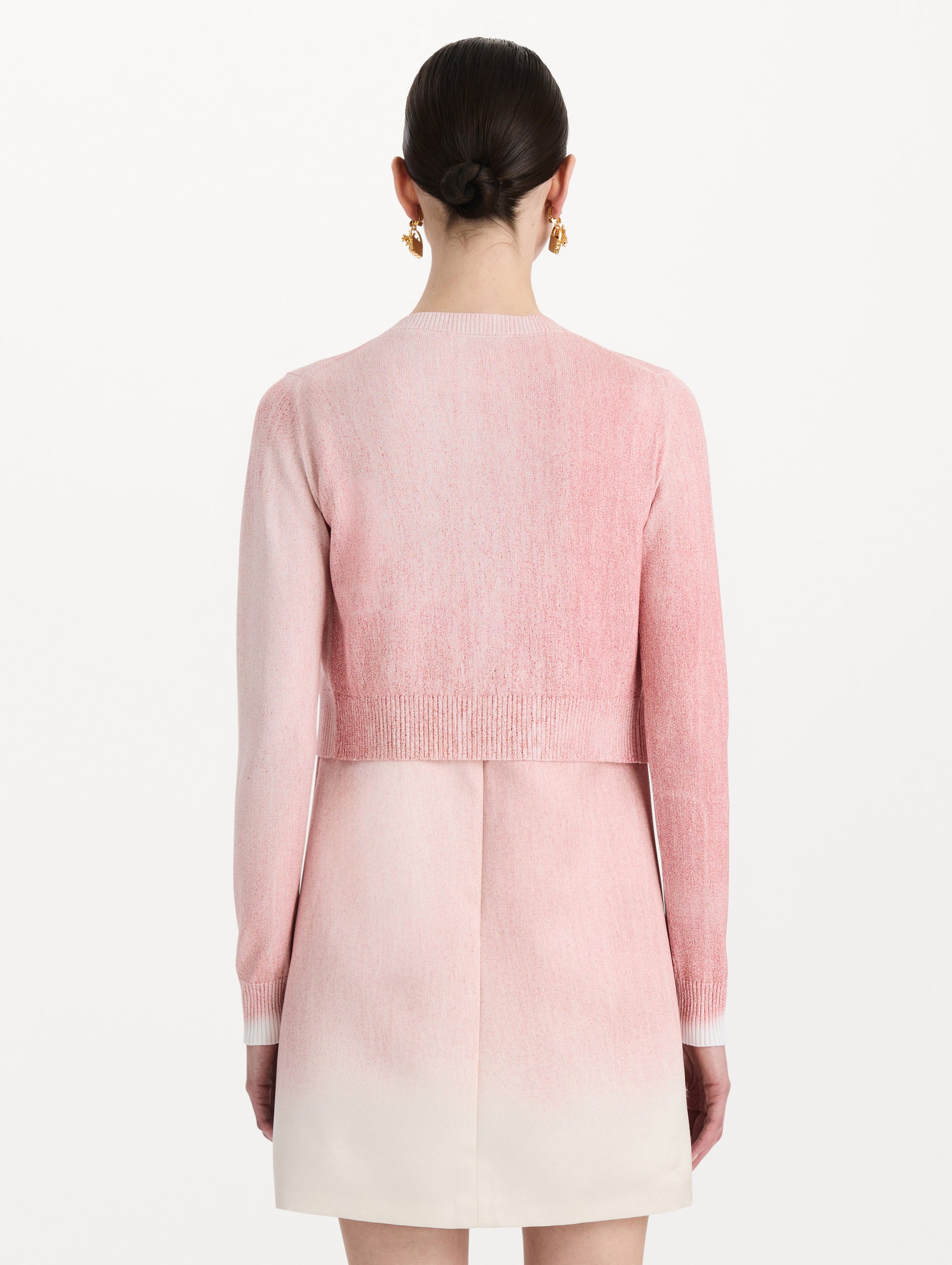 The model is wearing the botanical tie-neck cardigan with a floral print in the color blush. Back view.