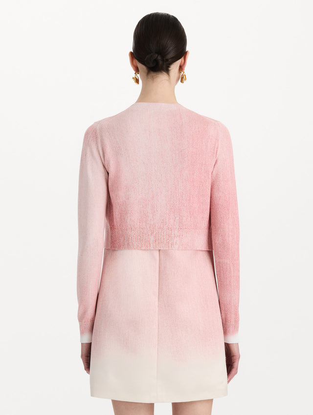 The model is wearing the botanical tie-neck cardigan with a floral print in the color blush. Back view.
