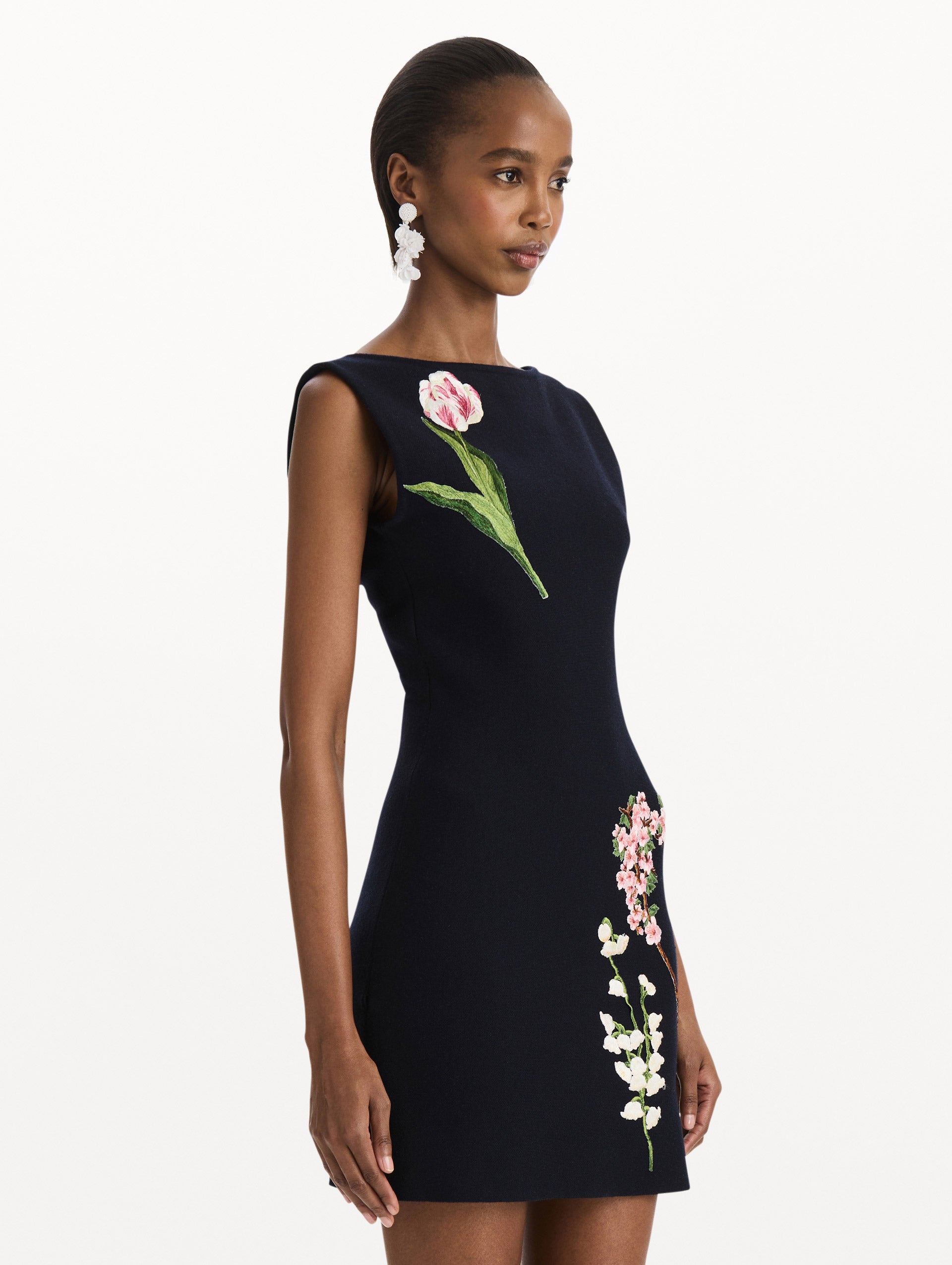 The model is wearing the mixed botanical embroidered dress with an A-line silhouette in a navy wool blend. Side view.