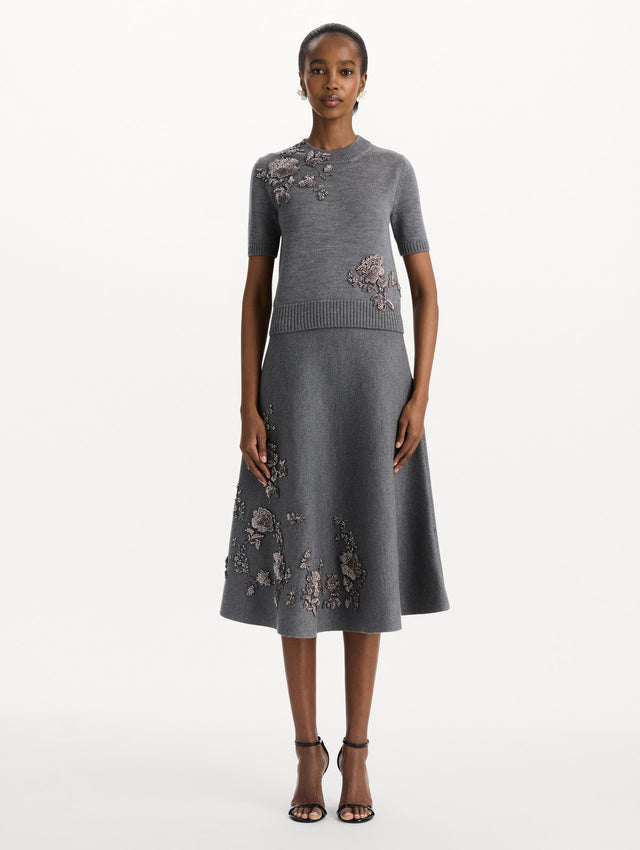 The model is wearing a beaded peony embroidered pullover in the color melange grey. Front view. 