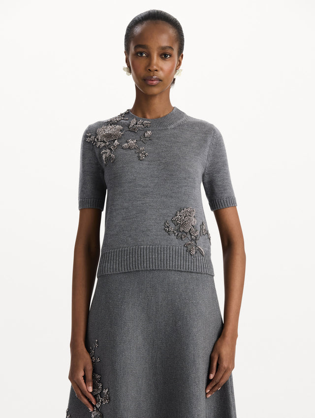 The model is wearing a beaded peony embroidered pullover in the color melange grey. Front view. 