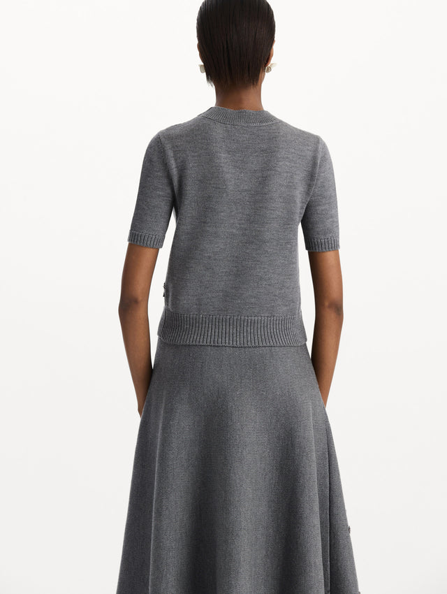 The model is wearing a beaded peony embroidered pullover in the color melange grey. Back view. 