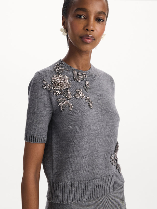 The model is wearing a beaded peony embroidered pullover in the color melange grey. Zoom view. 