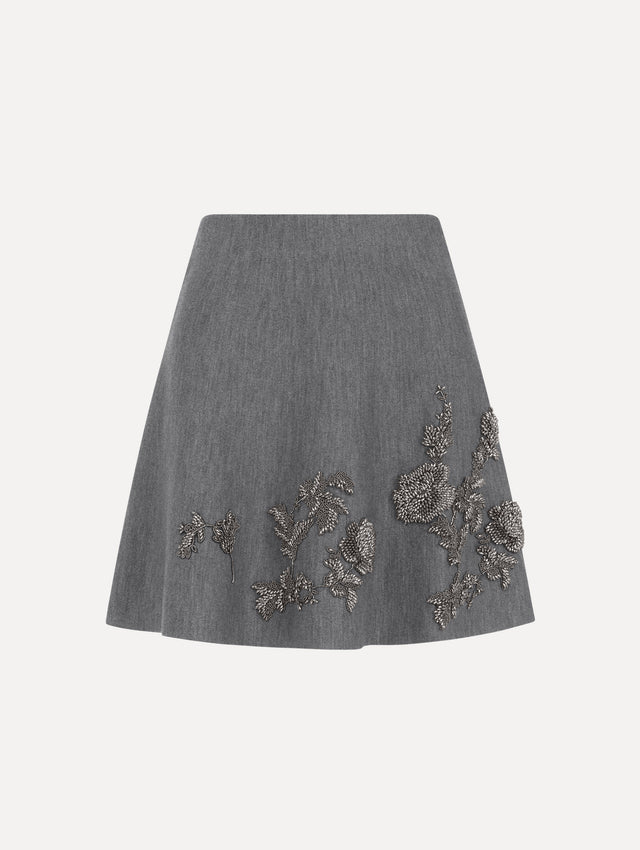 The model is wearing the beaded peony embroidered knit skirt in the color melange grey. 