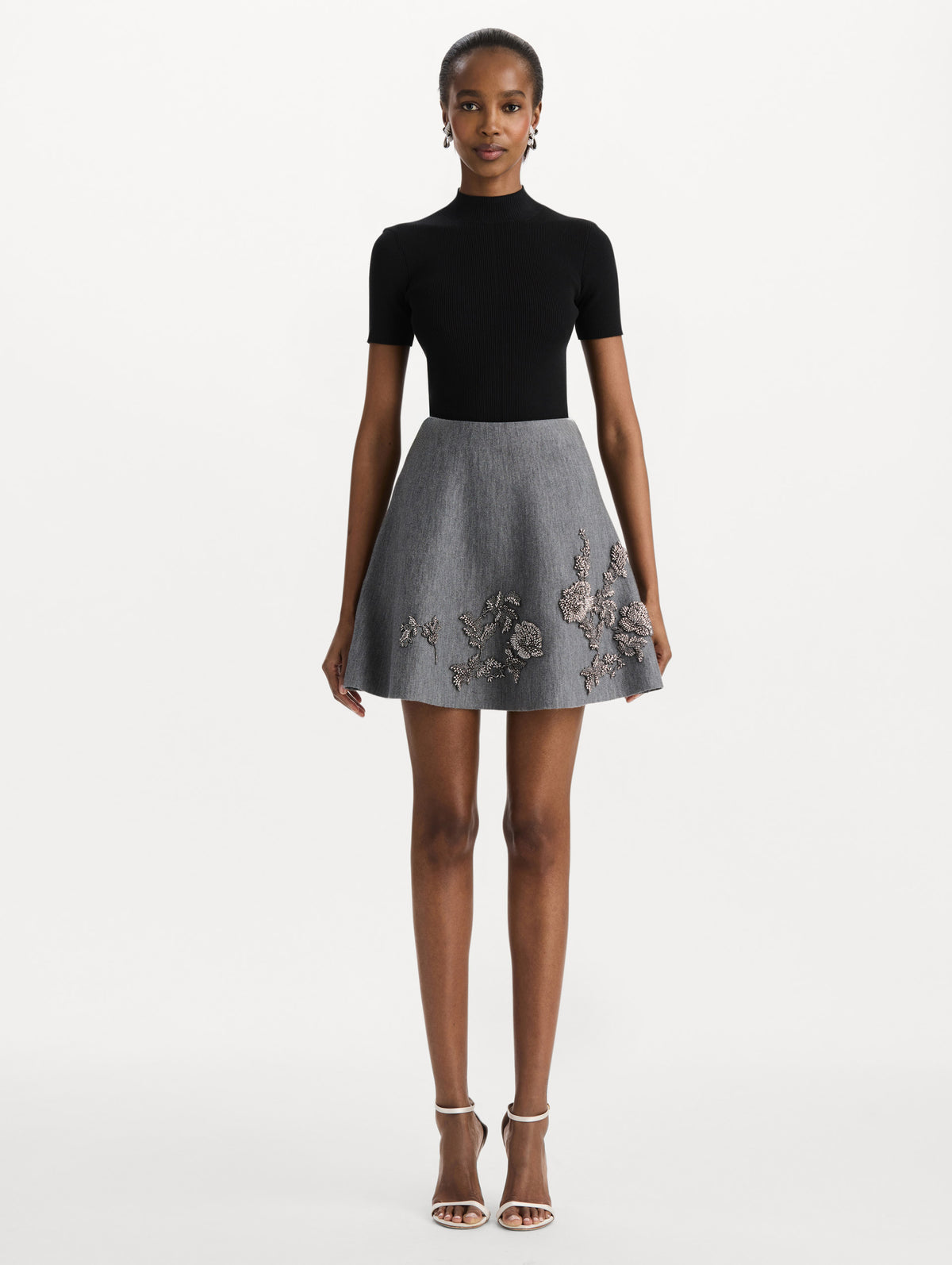 The model is wearing the beaded peony embroidered knit skirt in the color melange grey. Front view.