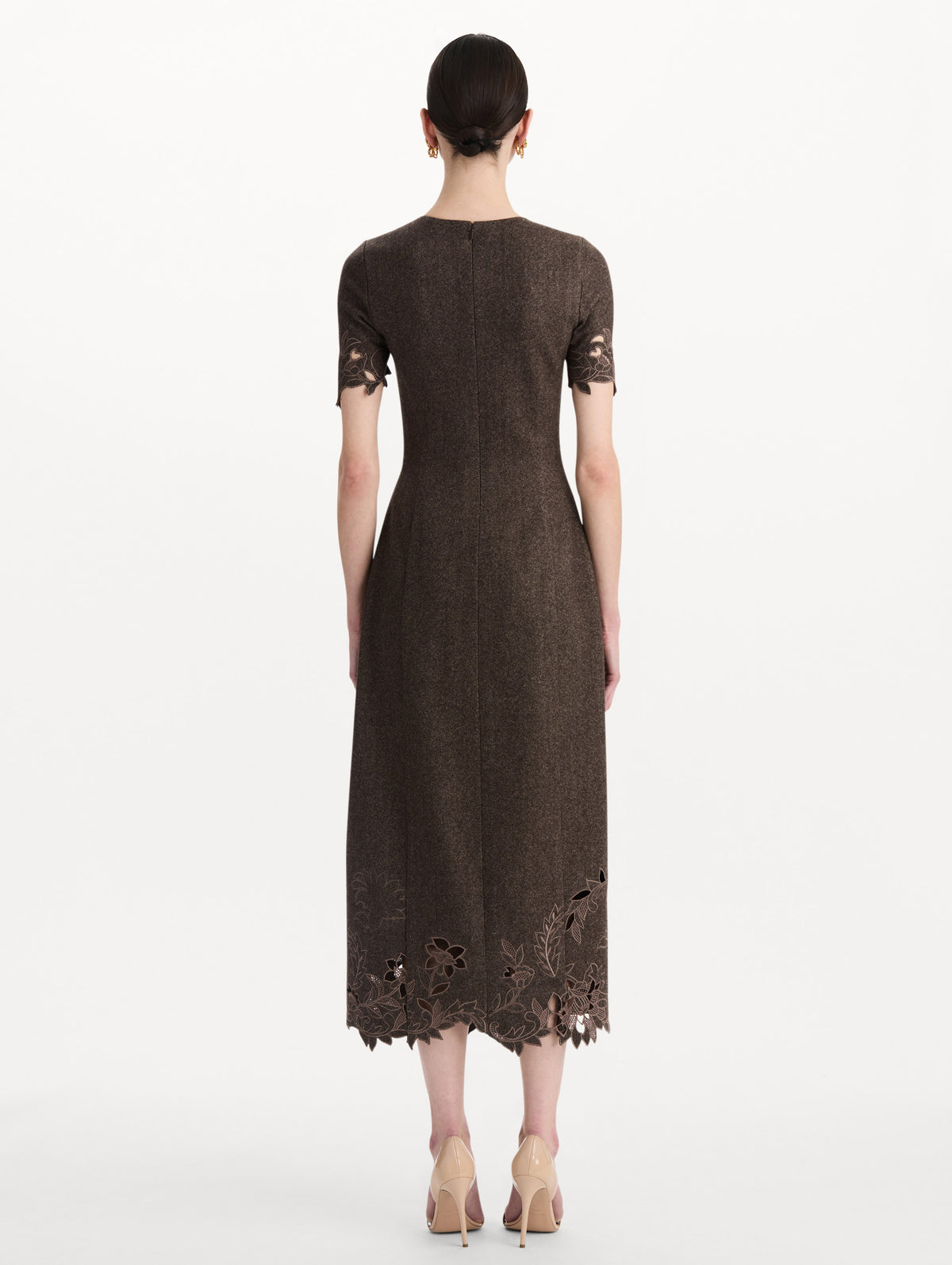 The model is wearing the peony cutout twill herringbone dress with short sleeves in a brown wool-cashmere blend. Back view.