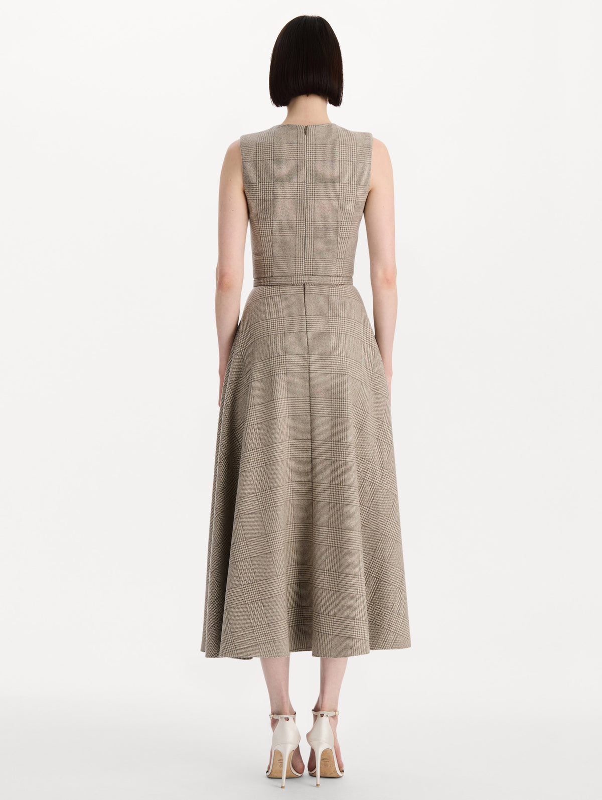 The model is wearing the plaid cashmere-blend dress with a sleeveless silhouette and a glen plaid pattern. Back view.