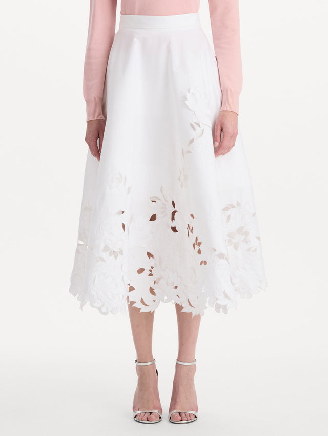 The model is wearing the floral cutout cotton twill skirt with botanical embroidery and a full silhouette in the color white. Front view.