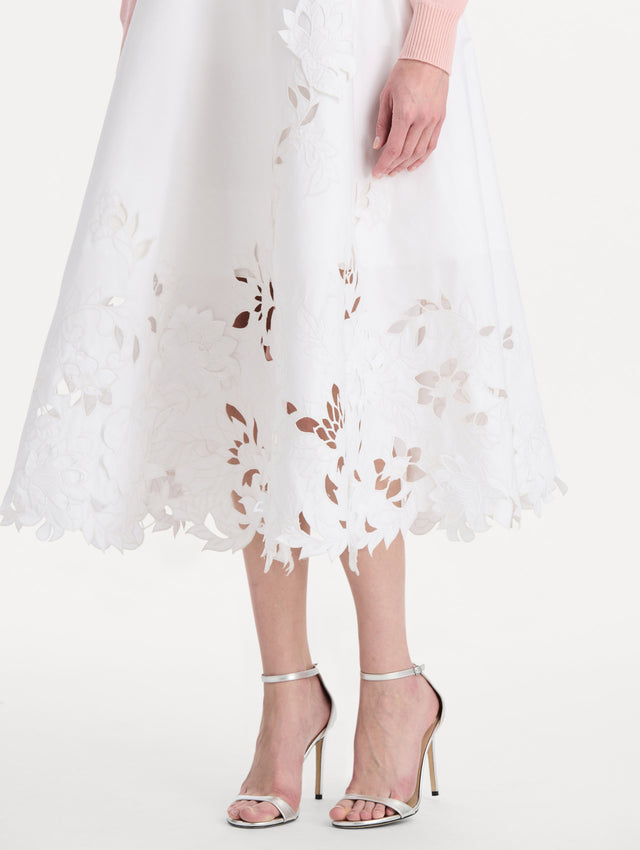 The model is wearing the floral cutout cotton twill skirt with botanical embroidery and a full silhouette in the color white. Zoom view.