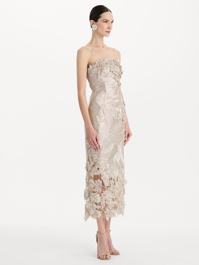 The model is wearing the intarsia leaves cutout embroidered cocktail dress with a strapless silhouette in the color silver. Side view.