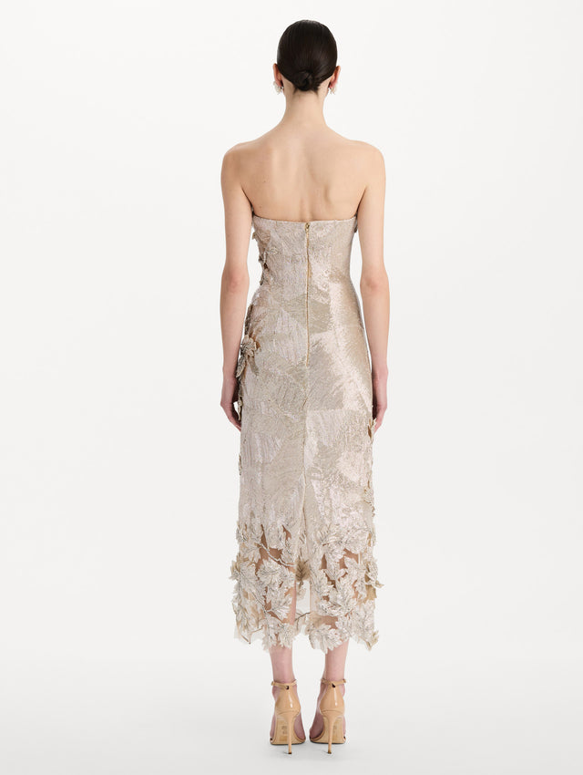 The model is wearing the intarsia leaves cutout embroidered cocktail dress with a strapless silhouette in the color silver. Back view.