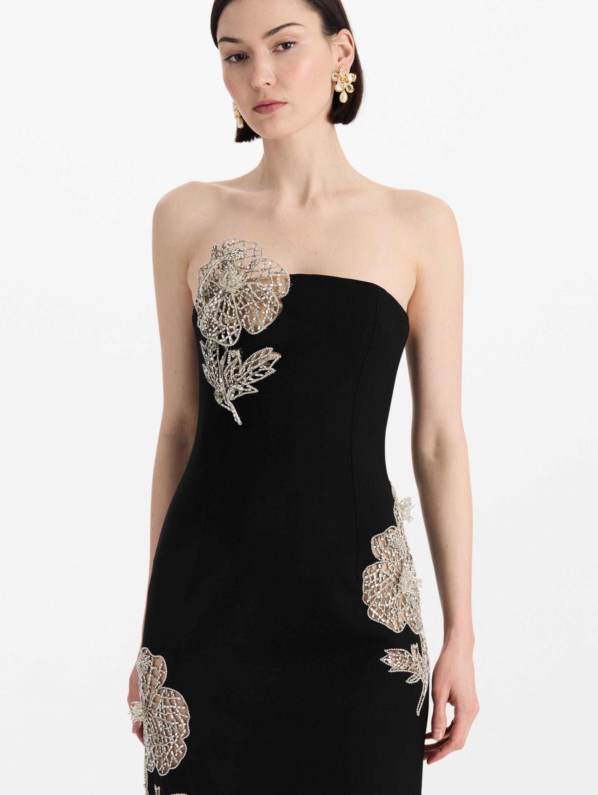 The model is wearing the crystal leaves embroidered cocktail dress with a strapless silhouette in the color black. Zoom view. 