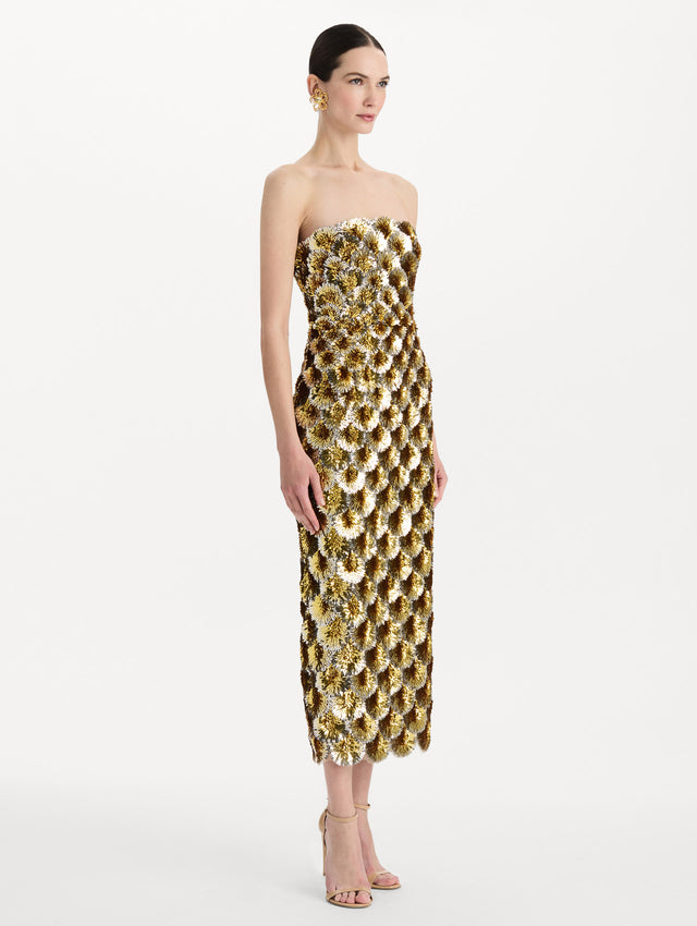 The model is wearing the sequin embroidered scalloped cocktail dress with a strapless, sculptural silhouette in the color yellow. Side view. 