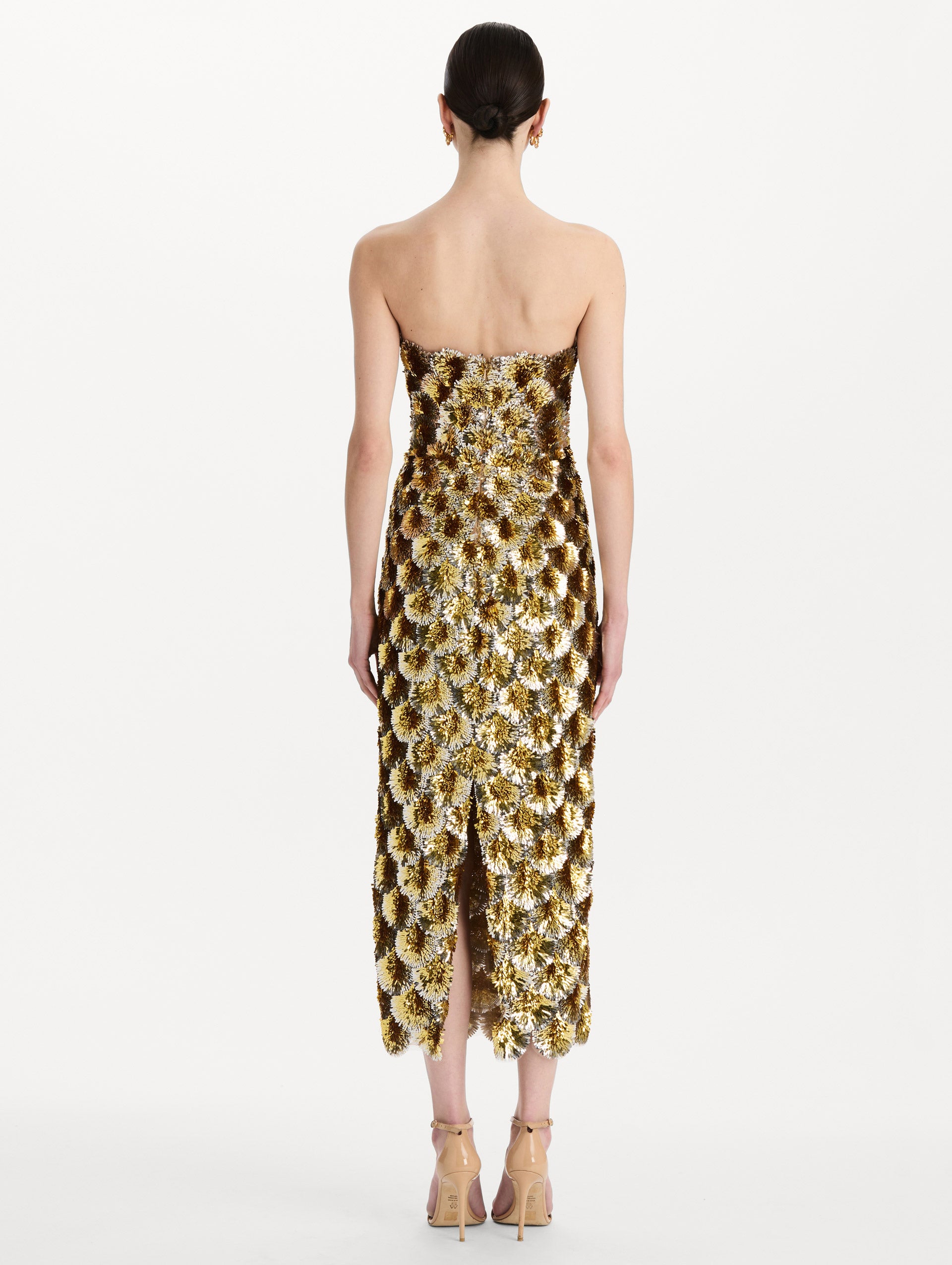 The model is wearing the sequin embroidered scalloped cocktail dress with a strapless, sculptural silhouette in the color yellow. Back view. 