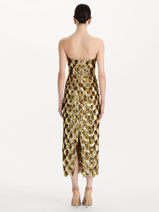 The model is wearing the sequin embroidered scalloped cocktail dress with a strapless, sculptural silhouette in the color yellow. Back view. 
