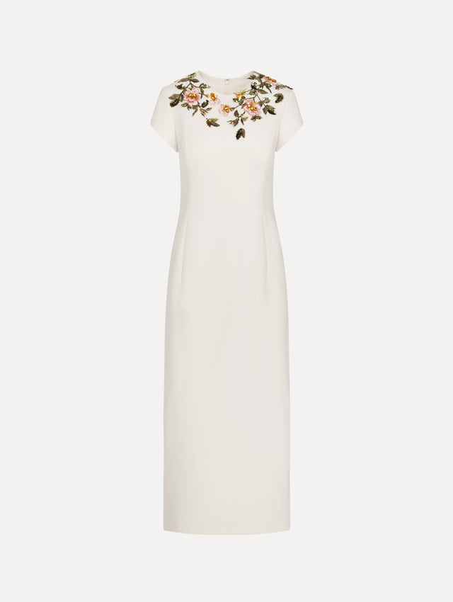 The model is wearing the beaded floral embroidered pencil dress with short sleeves in the color ivory.