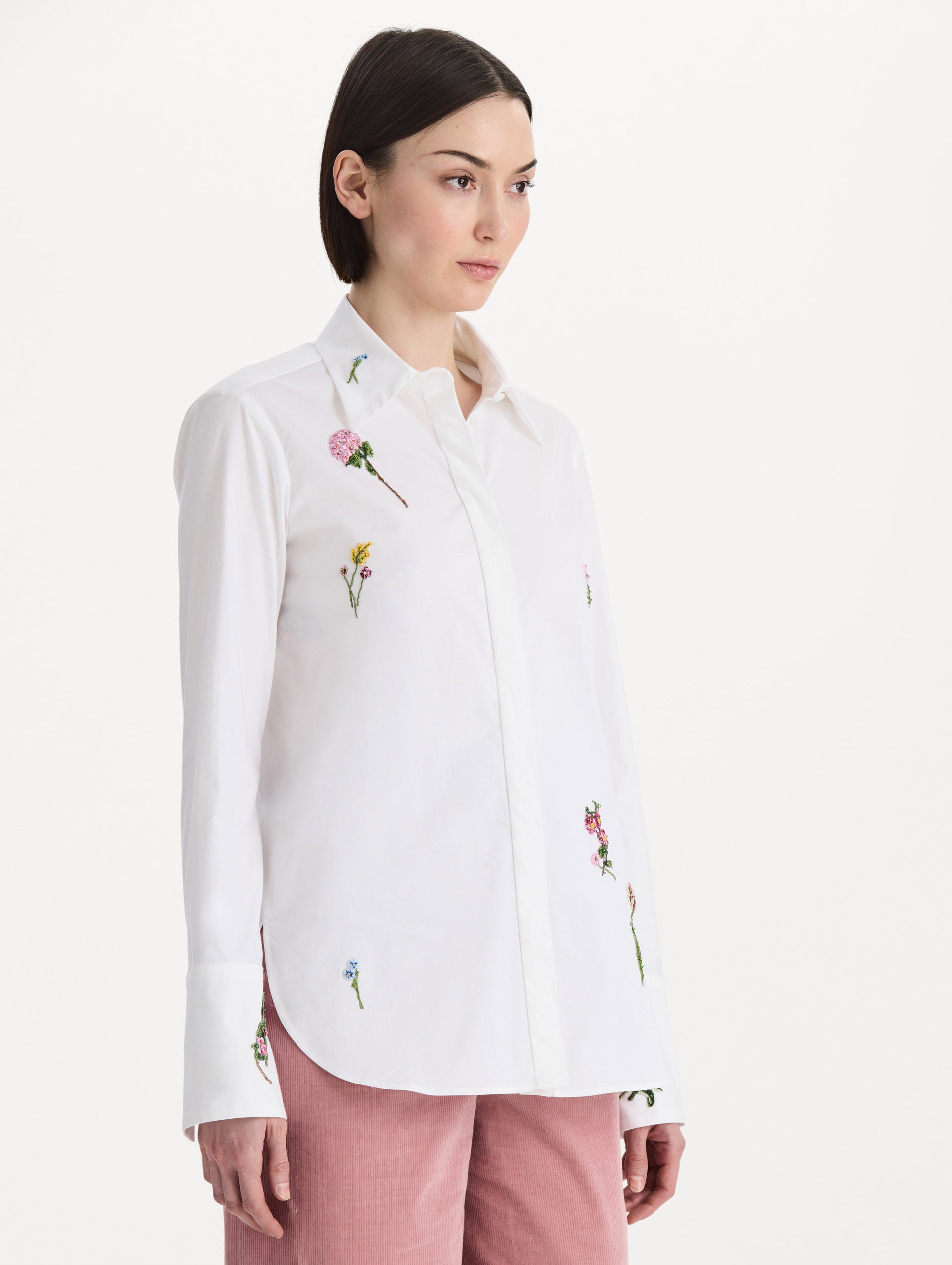 The model is wearing the beaded mixed botanical stretch twill blouse with long sleeves in the color white. Side view.