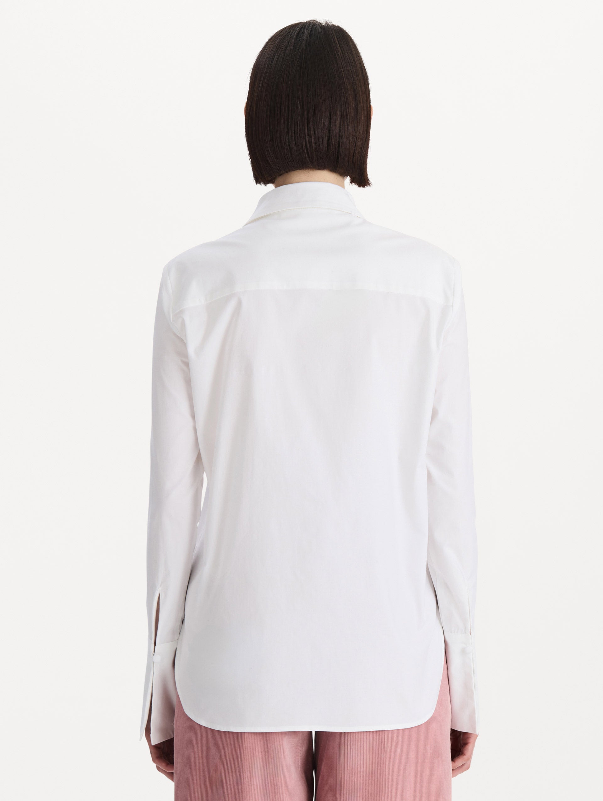 The model is wearing the beaded mixed botanical stretch twill blouse with long sleeves in the color white. Back view. 