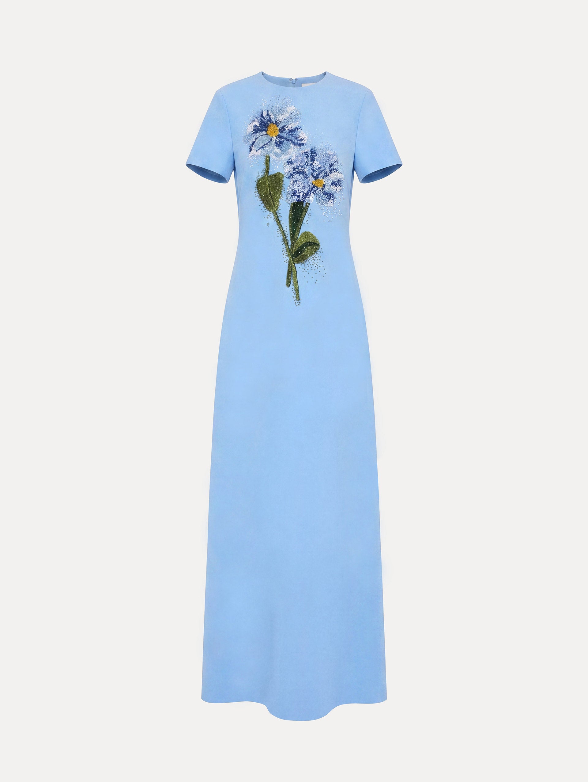 The model is wearing the beaded chiné cosmos embroidered caftan with short sleeves in the color talc blue.