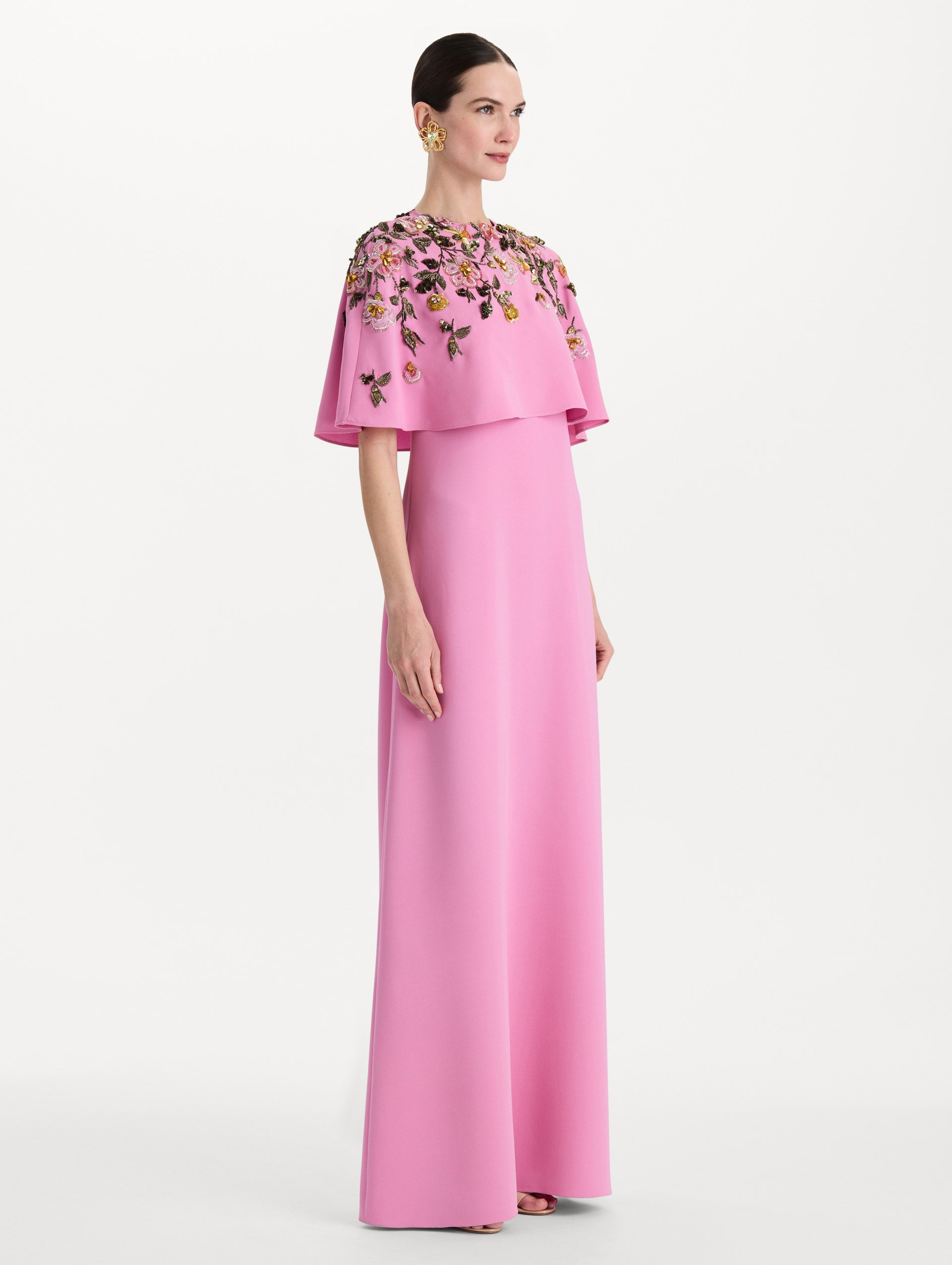 The model is wearing the beaded mixed botanical embroidered caftan in the color pink with floral detailing. Side view. 