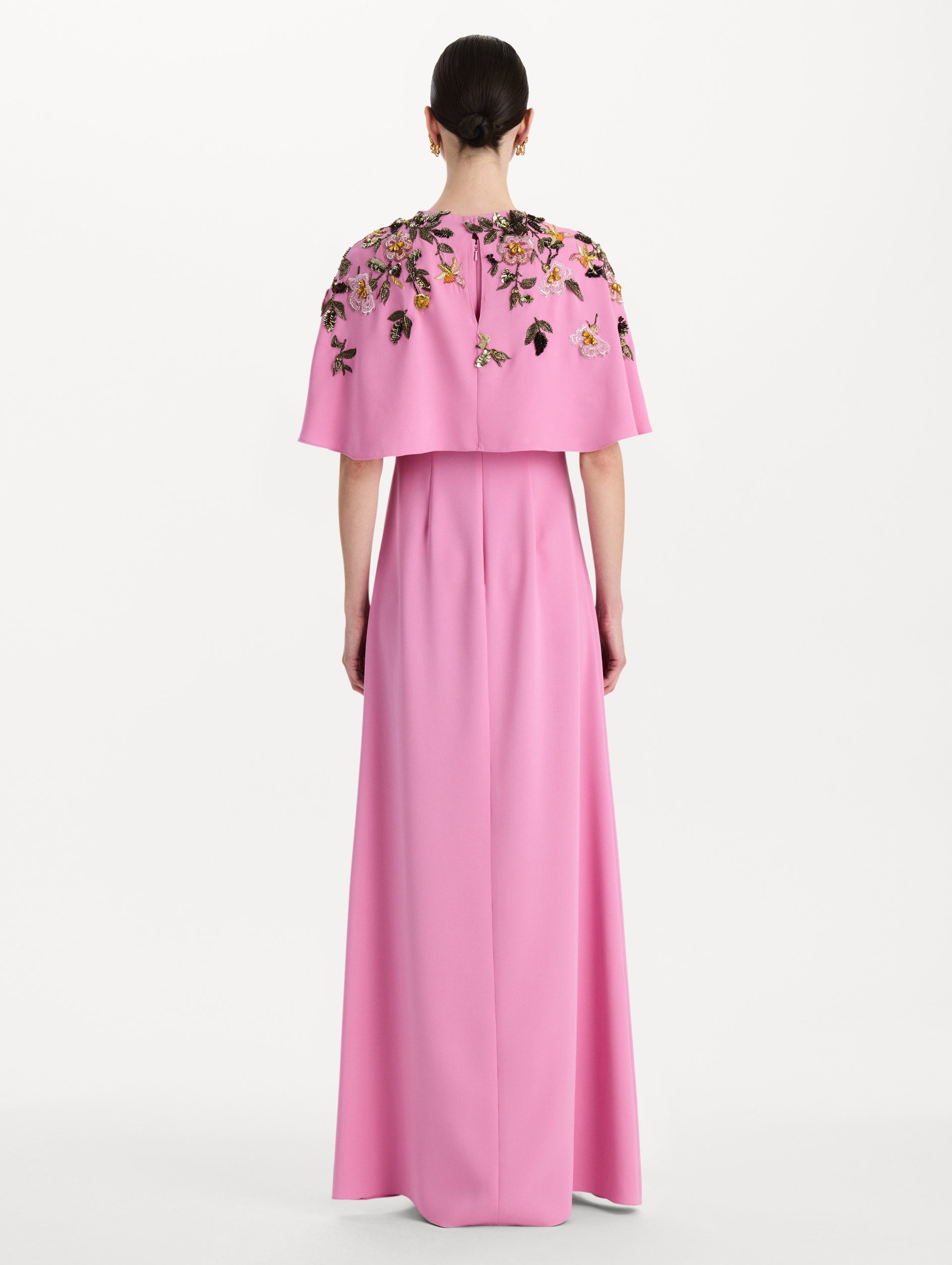 The model is wearing the beaded mixed botanical embroidered caftan in the color pink with floral detailing. Back view. 