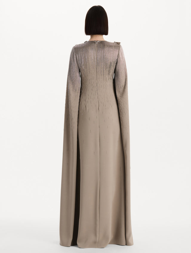 The model is wearing the intarsia leaves cutout embroidered caftan with long sleeves in the color stone. Back view. 