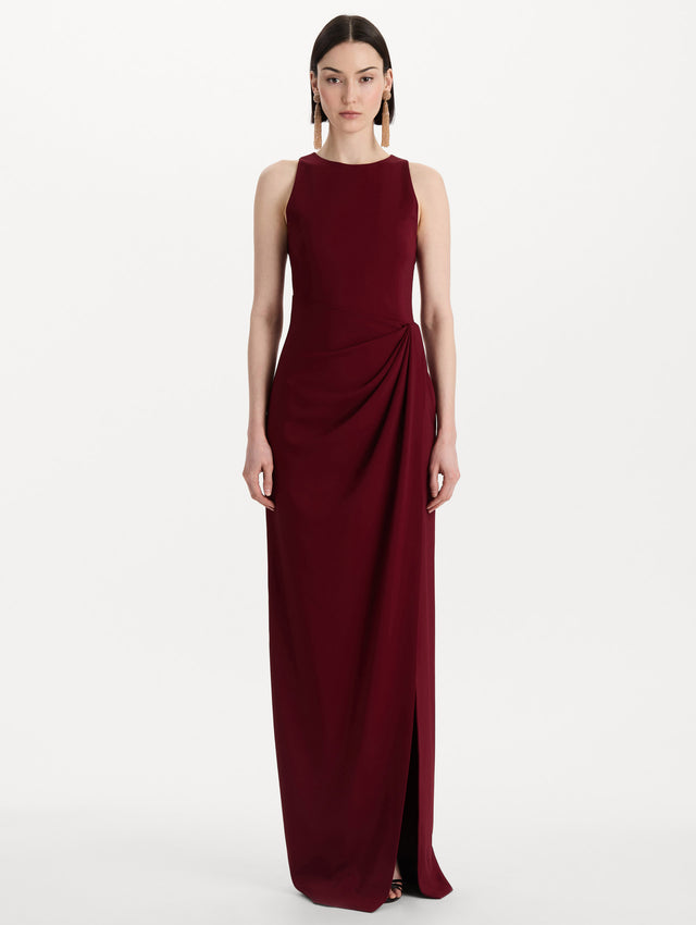 The model is wearing the drape-detailed cady gown with a sleeveless silhouette in the color claret. Front view. 