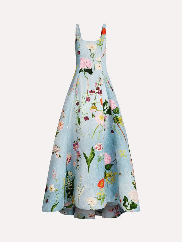 The model is wearing the mixed botanical faille gown with a sleeveless scoop neckline and a bold floral print in blue multi. 