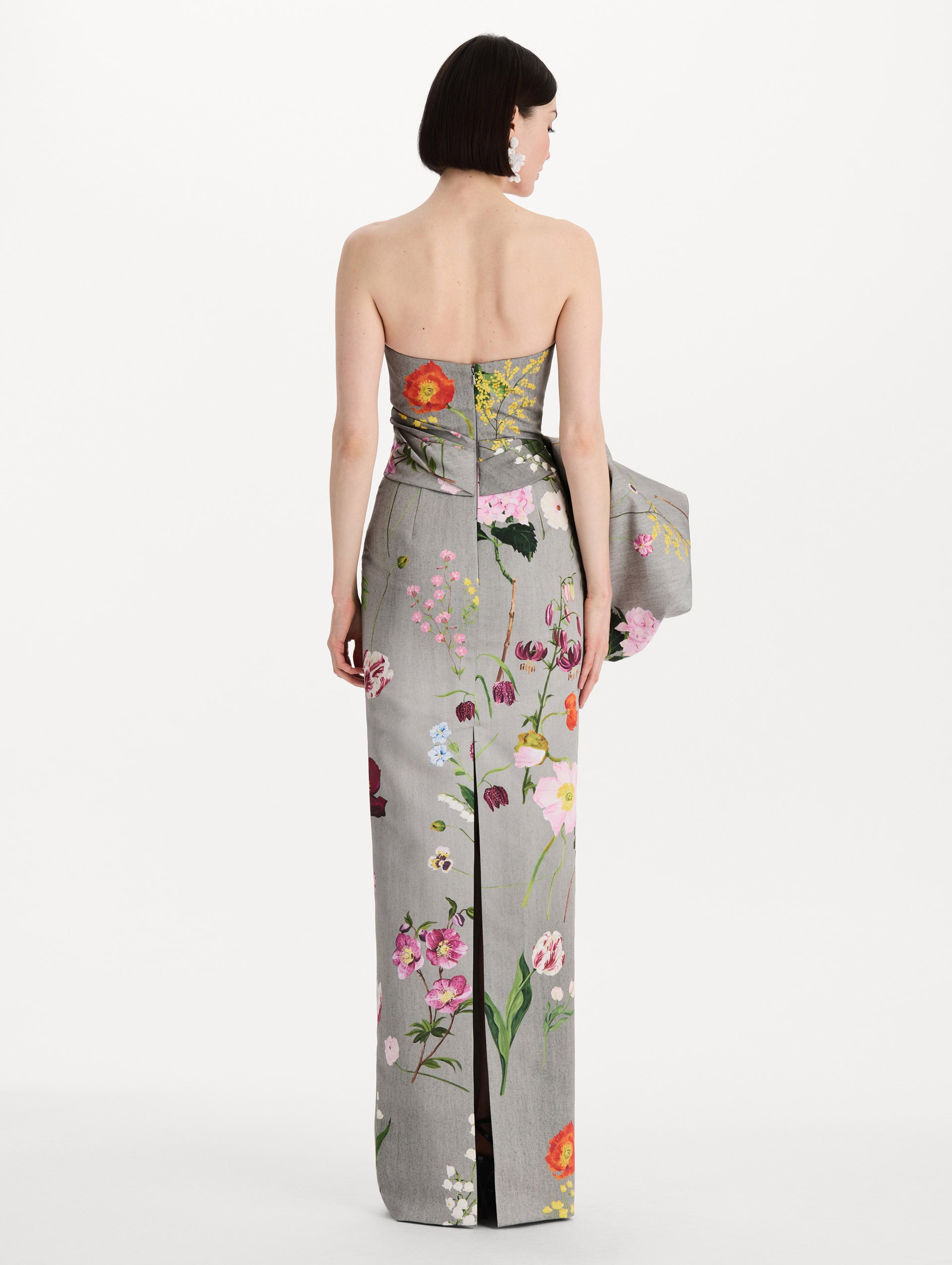 The model is wearing the mixed botanical drape-detailed faille gown with a strapless silhouette in the color grey multi. Back view. 