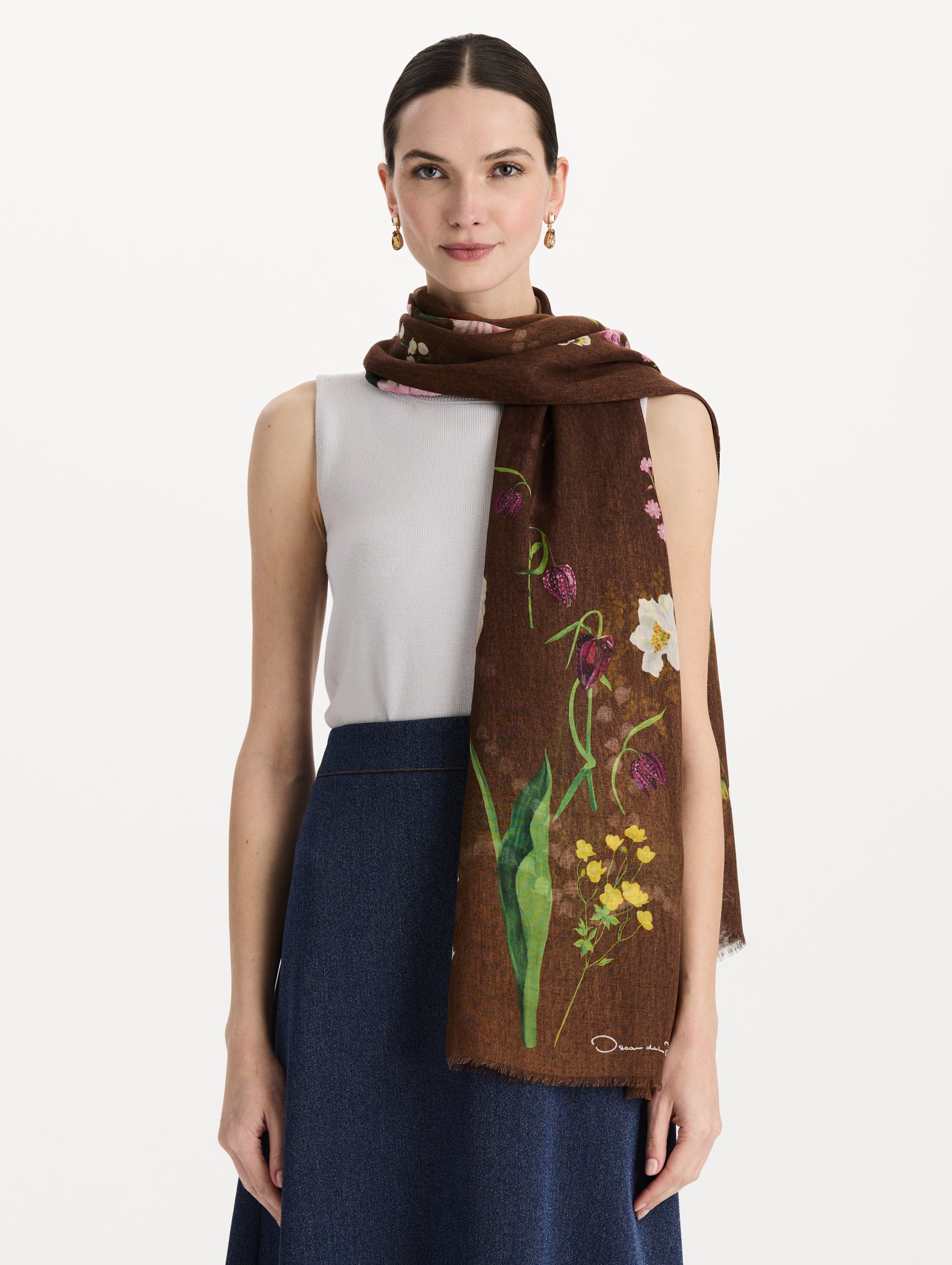 The model is wearing the mixed botanical scarf with an all-over floral print in the color brown. Front view. 