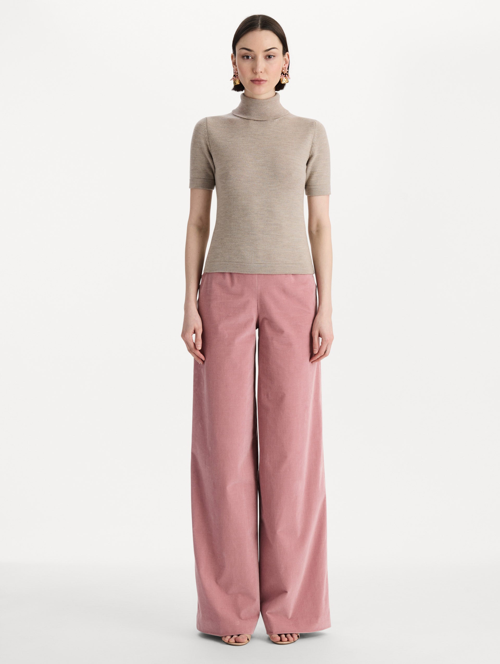 The model is wearing the turtleneck wool short-sleeve pullover with a fold-over neckline in the color dark oat. Front view. 