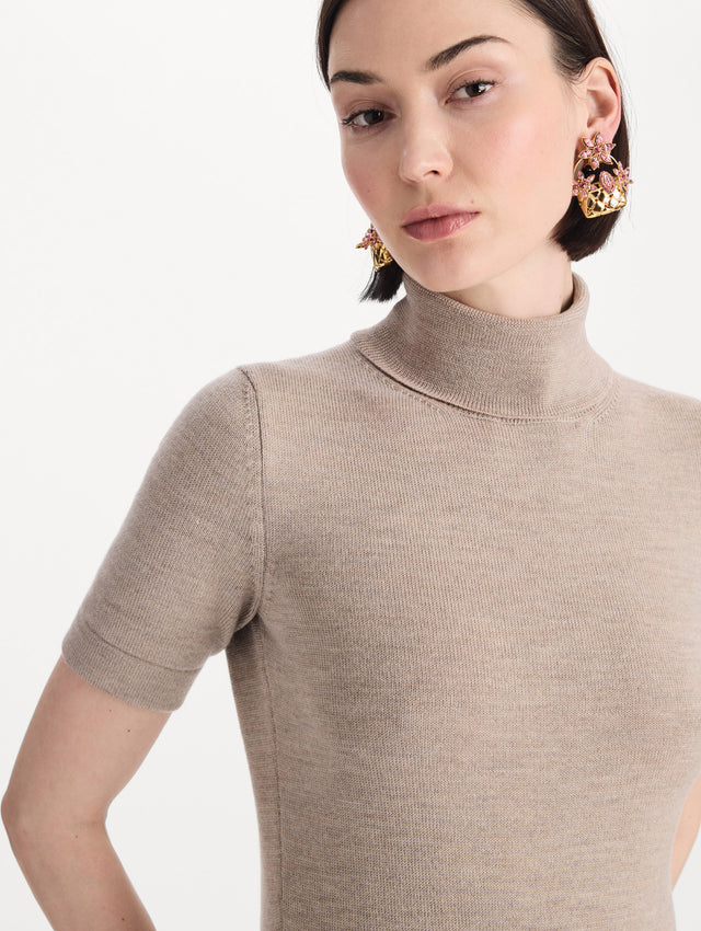 The model is wearing the turtleneck wool short-sleeve pullover with a fold-over neckline in the color dark oat. Zoom view. 