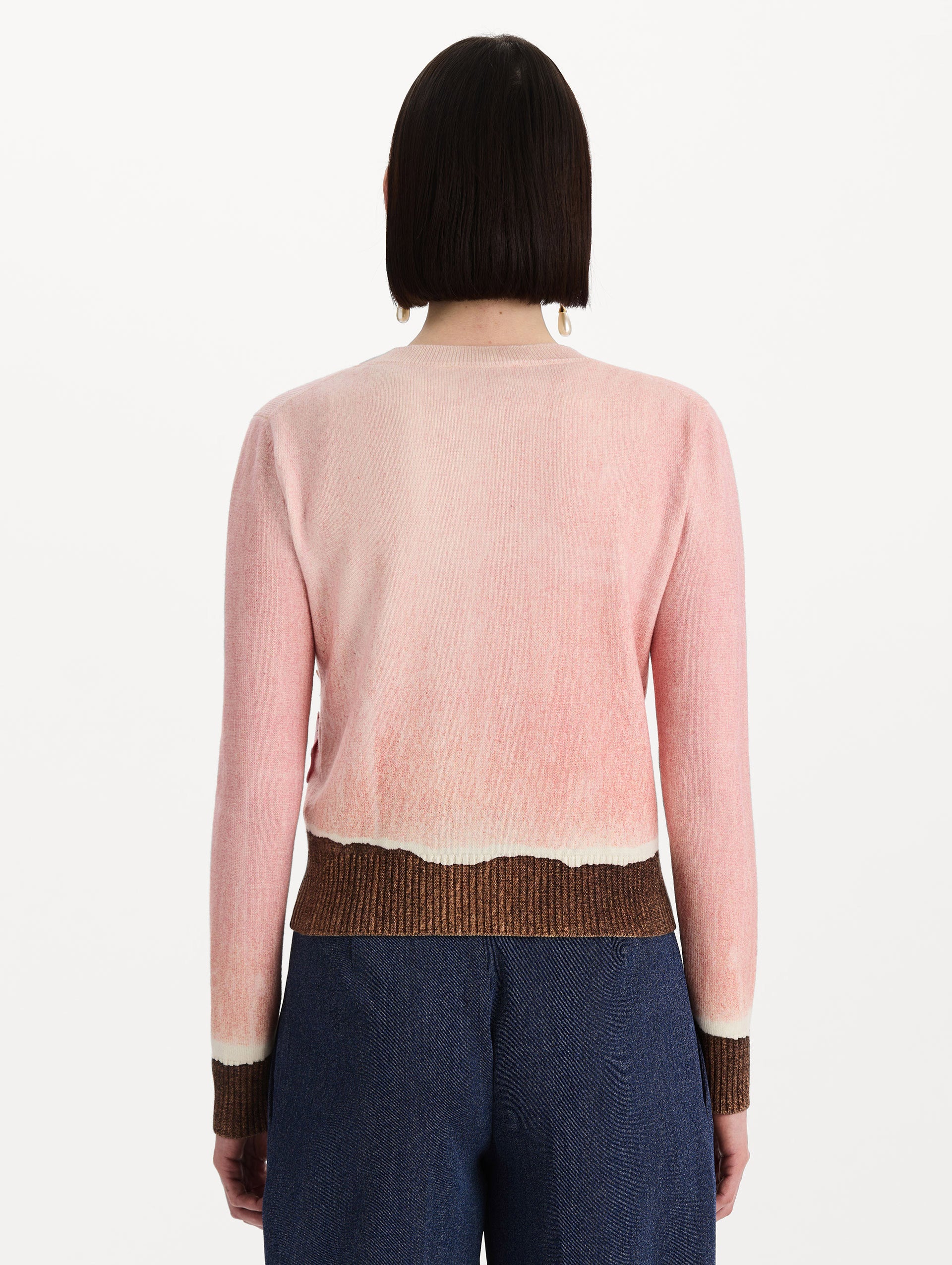 The model is wearing the ombré crewneck pullover with a painterly print in a pink and brown palette. Back view.