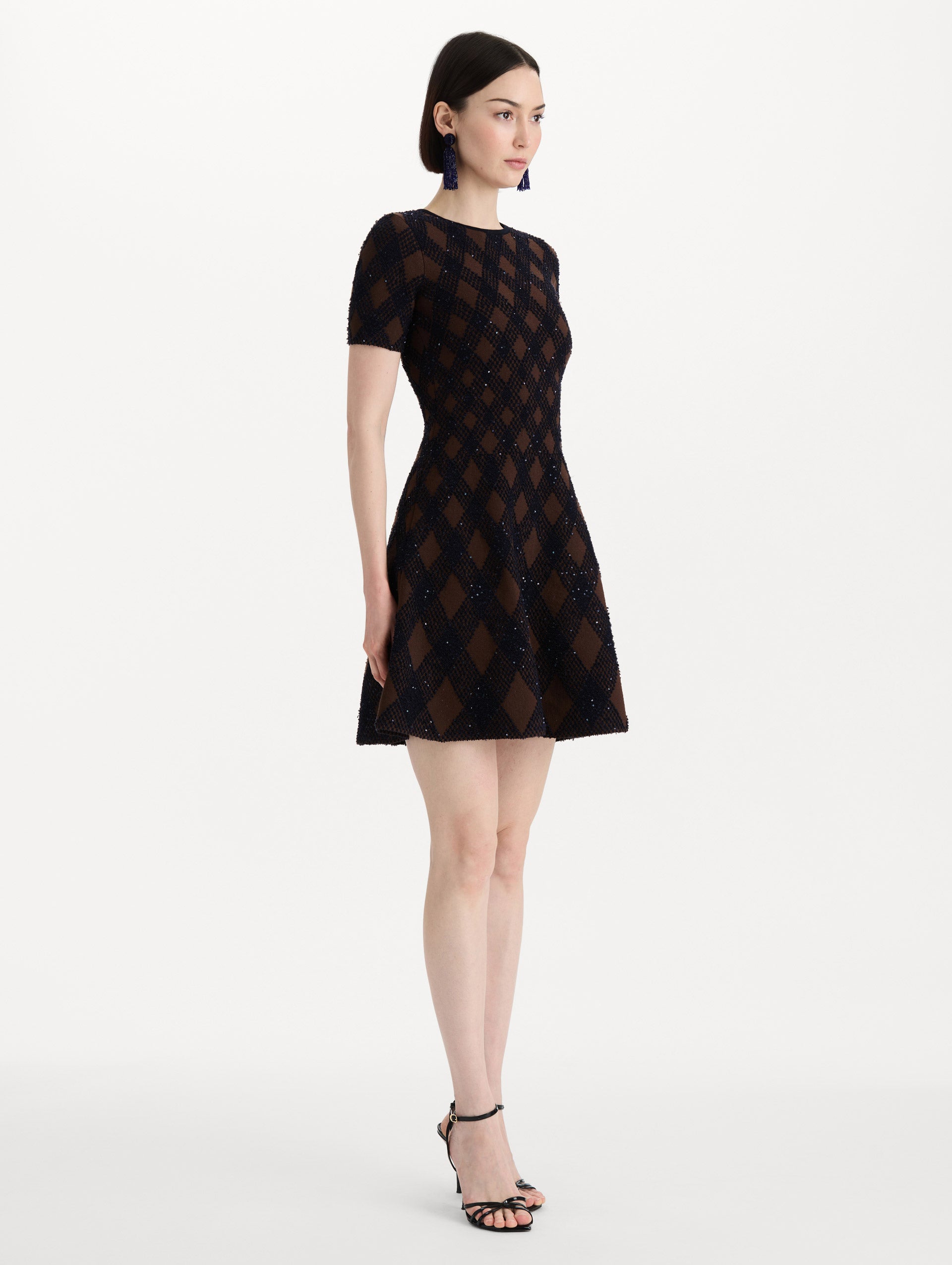 The model is wearing the argyle knit dress with a fit-and-flare silhouette in navy and brown. Side view. 