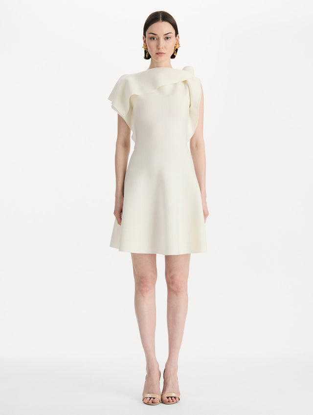 The model is wearing the drape-detailed knit dress with a draped neckline in the color ivory. Front view. 
