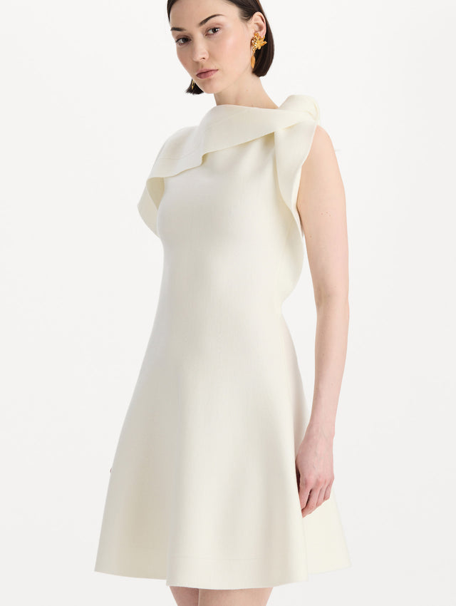 The model is wearing the drape-detailed knit dress with a draped neckline in the color ivory. Zoom view. 