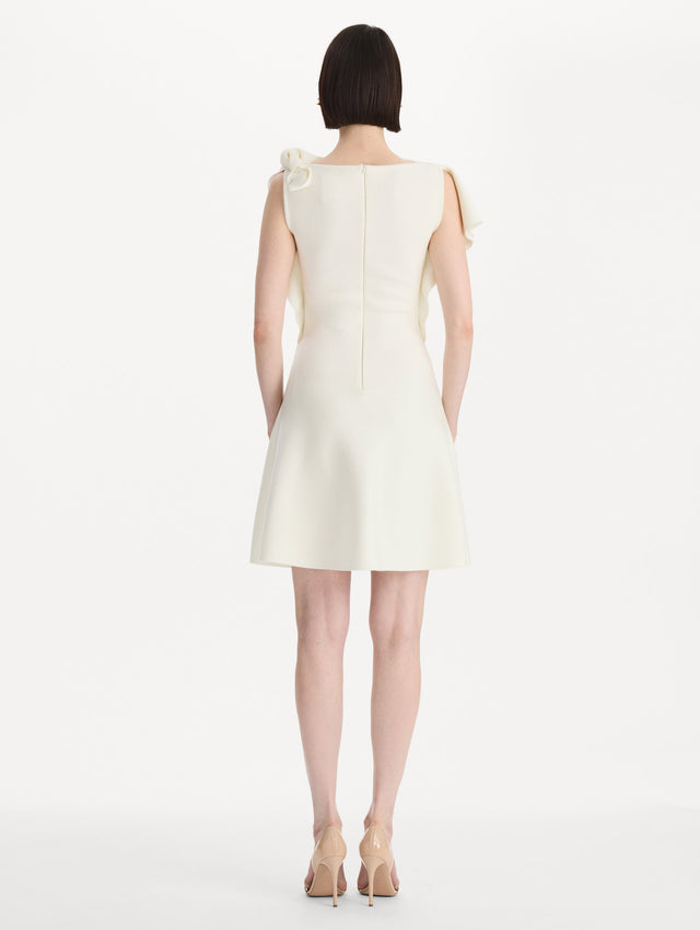 The model is wearing the drape-detailed knit dress with a draped neckline in the color ivory. Back view. 