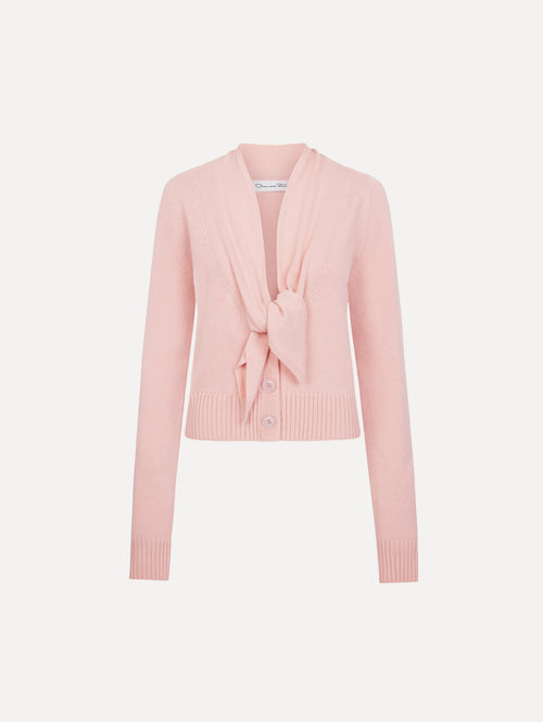 The model is wearing the tie-neck cardigan in blush wool with a tie V-neck detail. 