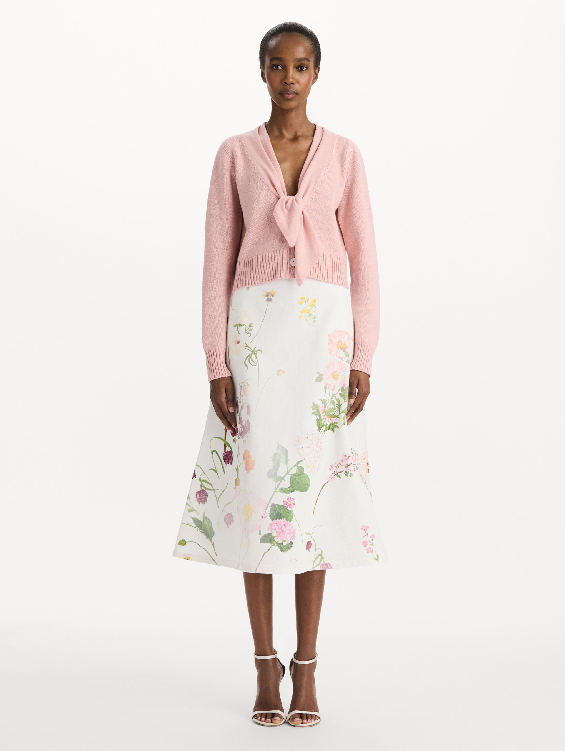 The model is wearing the tie-neck cardigan in blush wool with a tie V-neck detail. Front view.