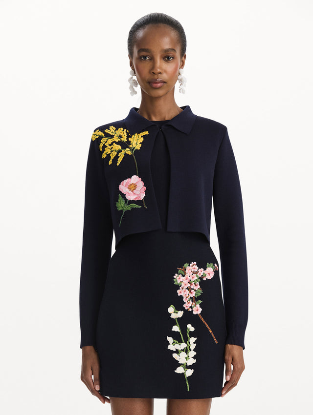 The model is wearing the mixed botanical cropped jacket with delicate embroidery in the color navy. Front view.