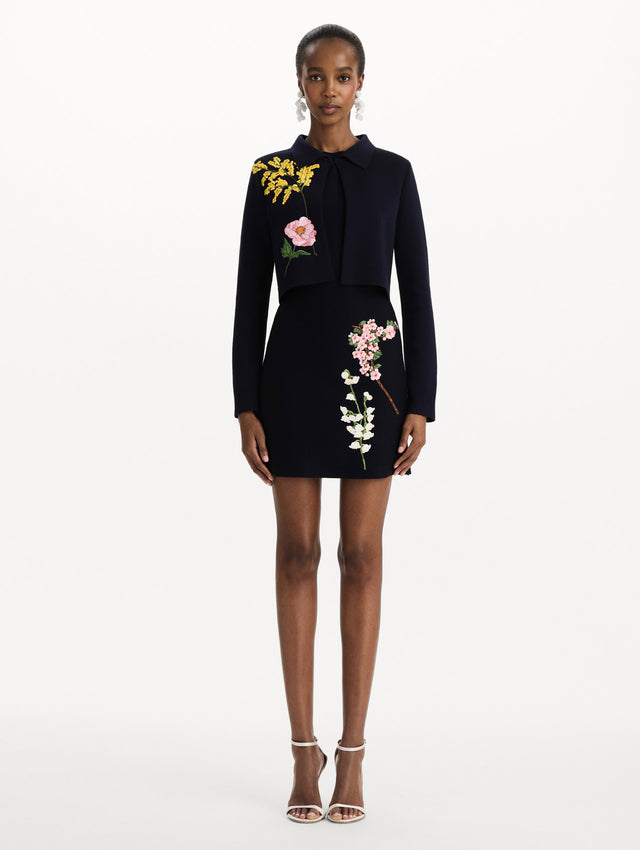 The model is wearing the mixed botanical cropped jacket with delicate embroidery in the color navy. Front view.