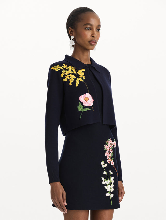The model is wearing the mixed botanical cropped jacket with delicate embroidery in the color navy. Side view.