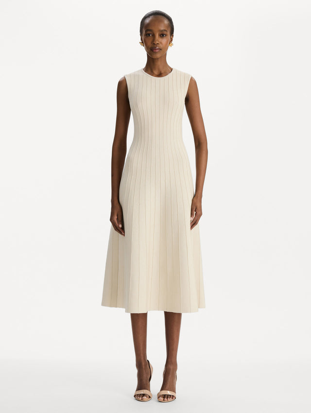 The model is wearing the ottoman knit dress in the color ivory with metallic sparkle yarn detailing. Front view.