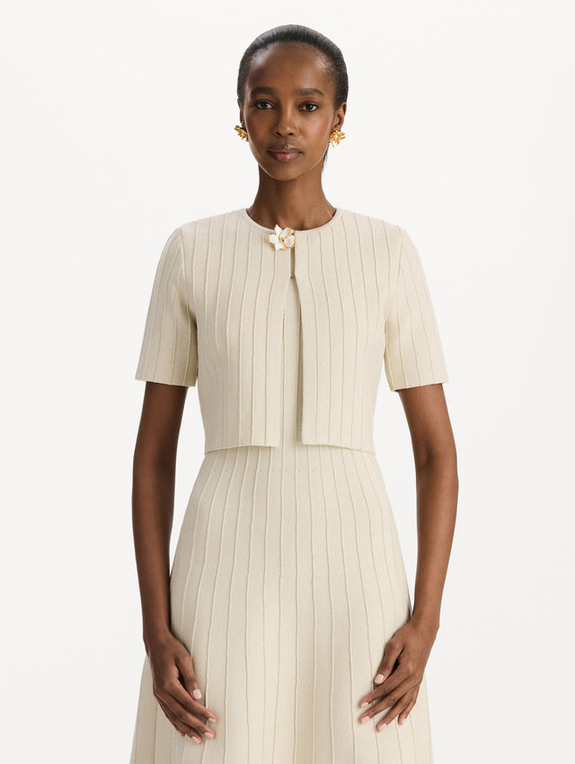 The model is wearing the ottoman cropped cardigan with sparkle yarn detailing in the color ivory. Front view.