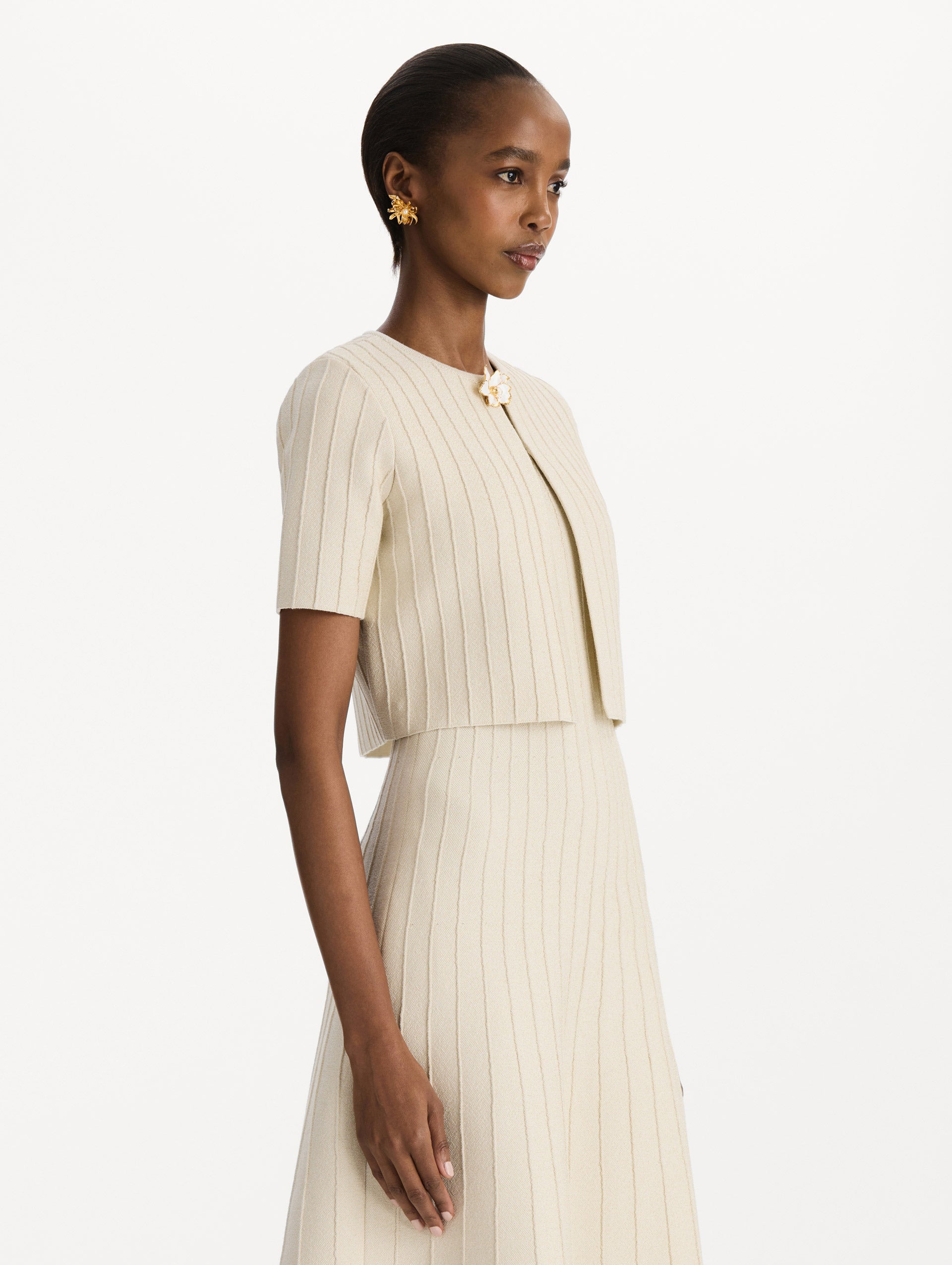 The model is wearing the ottoman cropped cardigan with sparkle yarn detailing in the color ivory. Side view.