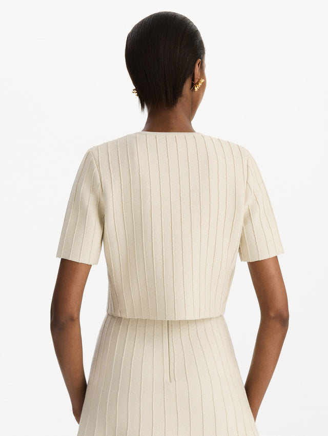 The model is wearing the ottoman cropped cardigan with sparkle yarn detailing in the color ivory. Back view.